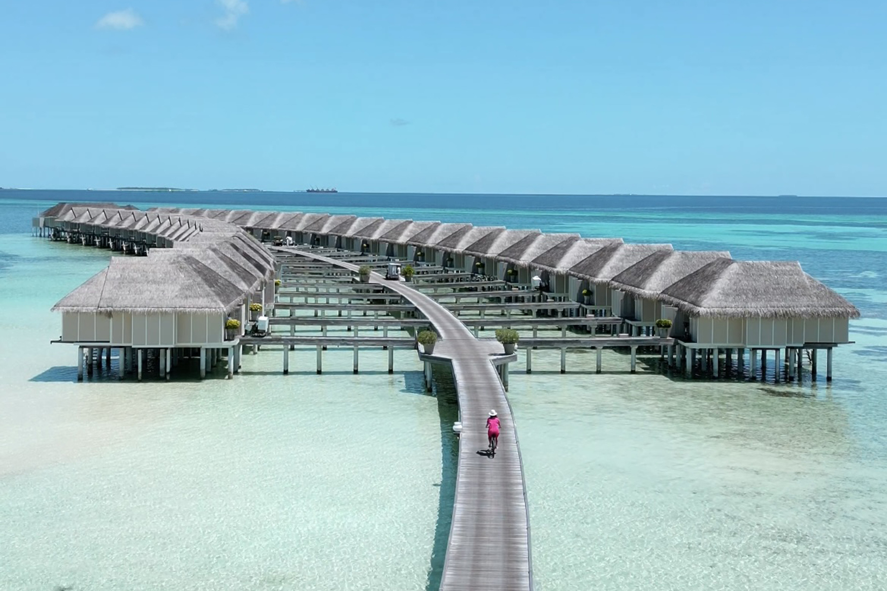 Drone footage of water villas and biking woman